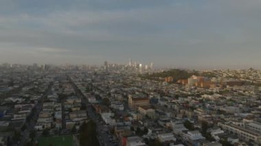 Şehir merkezindeki uzun düz sokaklar boyunca konut evlerinin üzerinden uç. Uzaktaki modern yüksek katlı ofis binaları. San Francisco, California, ABD