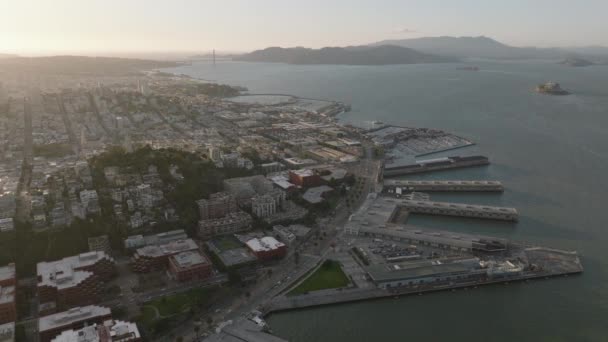 コーストの上を飛ぶ 夕暮れ時の都市 都市の水と町の開発に突き出た桟橋の空中ビュー 米国カリフォルニア州サンフランシスコ — ストック動画
