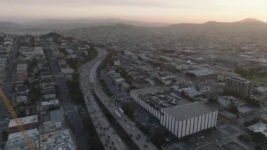 İleriye doğru alacakaranlıkta büyük şehrin üzerinde uçar. Çevre yolunda yoğun trafik var. Şehir merkezine doğru gidiyor. San Francisco, California, ABD