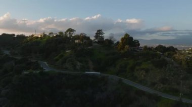 İleri, büyük şehrin tepelerindeki lüks evlerinin üzerinden uçar. Alacakaranlıktaki şehir merkezinin hava görüntüleri. Los Angeles, Kaliforniya, ABD.