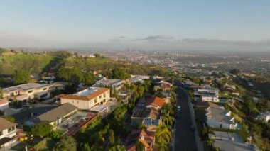 Metropolün yukarısındaki tepelerdeki lüks evlerin üzerinde altın saat güneş ışığıyla aydınlatılan evler uçuyor. Los Angeles, Kaliforniya, ABD.