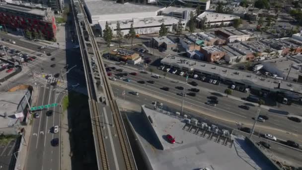 交差点前の多車線道路の信号場に停車する車の高い角度の眺め 交差点の上の橋の上の鉄道 米国カリフォルニア州ロサンゼルス — ストック動画