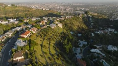Tepedeki konutların inanılmaz görüntüleri öğleden sonra güneşiyle aydınlatılıyor. Arka planda büyük bir şehir. Los Angeles, Kaliforniya, ABD.