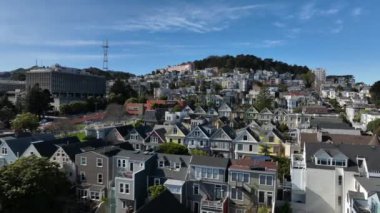 Şehrin üzerinde yükselen yamaçtaki renkli konut evlerinin üzerinden ileriye doğru uçuyor. San Francisco, California, ABD