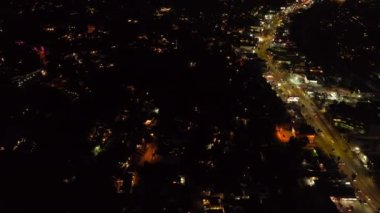 Gece şehrinin yüksek açılı manzarası. Azaltılmış yerleşim bölgesi ve parlak ışıklı alışveriş bulvarı. Romantik alacakaranlık gökyüzünü göster. Los Angeles, Kaliforniya, ABD.