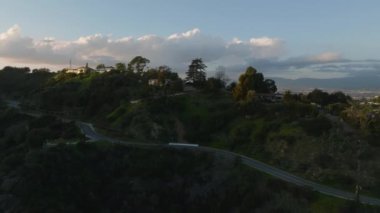 İleri, büyük şehrin tepelerindeki lüks evlerinin üzerinden uçar. Alacakaranlıktaki şehir merkezinin hava görüntüleri. Los Angeles, Kaliforniya, ABD.