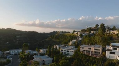 Altın saat 'te tepelik arazide yerleşim yerinin üzerinde ilerliyorlar. Yeşil ağaçlarla çevrili lüks evler. Los Angeles, Kaliforniya, ABD.