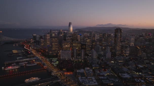 カラフルな夕暮れの空に対して海岸沿いのライトアップされたダウンタウンの高層ビルの素晴らしい空撮 米国カリフォルニア州サンフランシスコ — ストック動画