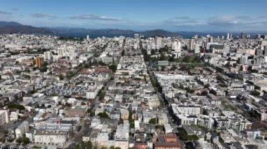 Şehir merkezindeki binaların üzerinden uçuyor. Su yüzeyi ve arka planda kıyı tepeleri. San Francisco, California, ABD