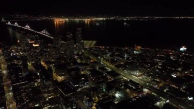 Yükseklerden sahil şeridinin gece görüntüsü. Otoyol ve Bay Köprüsü 'ndeki trafiğin hava görüntüleri. Su yüzeyi ışıkları yansıtıyor. San Francisco, California, ABD.