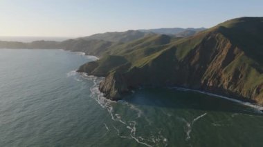 Sahildeki doğanın romantik sinematik görüntüleri. Alçak güneş uzun gölgeler yapıyor ve dalgalar kayalık kıyıları yıkıyor. San Francisco, California, ABD.