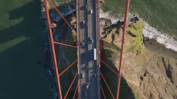 从上往下拍摄重要大道上的交通状况 在著名的金门大桥上的多车道路上行驶的车辆 落基海岸和波涛汹涌的海峡水 美国加利福尼亚州旧金山 — 图库视频影像