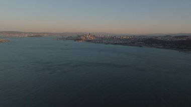 Büyük su yüzeyi ve metropolün alacakaranlıktaki hava panoramik görüntüleri. Geriye doğru geniş asma köprünün tepesini gösteriyor. San Francisco, California, ABD.