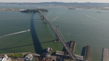 San Francisco körfezinin sularına yayılan Bay Köprüsü 'nün havadan görüntüsü. Altın saatte uzun asma köprüde yoğun trafik var. San Francisco, California, ABD.