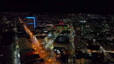 Gece belediye binasının hava kaydırak ve pan görüntüleri. Renkli ışıklarla aydınlatılmış tarihi eser. Şehir merkezinin panoramik görüntüsü. San Francisco, California, ABD.