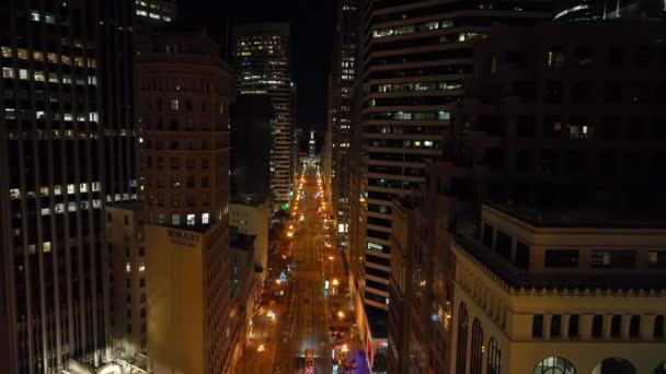 前方のライトアップされた通りの上の高層ビルに囲まれて飛ぶ 夜の金融街 米国カリフォルニア州サンフランシスコ — ストック動画