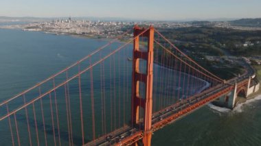 Arka planda uzun çelik köprü kulesinin ve metropolün hava görüntüleri var. Golden Gate Köprüsü 'nde trafik var. San Francisco, California, ABD.