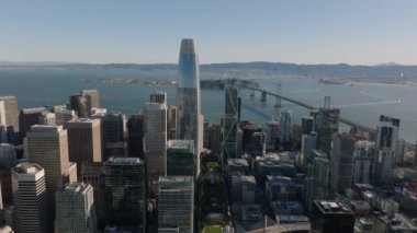 Şehir merkezindeki gökdelenlerin, Long Bay Köprüsü 'nün ve altın saatinde geniş su yüzeyinin hava sineması görüntüleri. San Francisco, California, ABD.