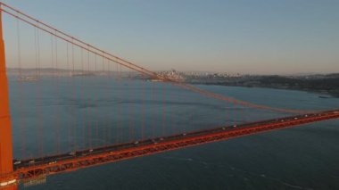 Ünlü Golden Gate Köprüsü 'nün inanılmaz sinematik görüntüleri ve arka plandaki şehirdeki binalar. Güneşin batışıyla aydınlanıyor. San Francisco, California, ABD.