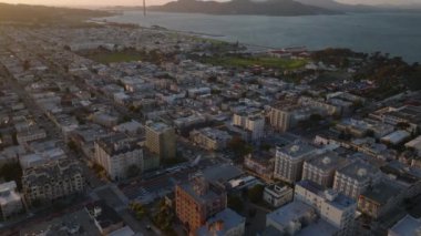 Alacakaranlıktaki kentsel binaların yüksek açılı manzarası. Yükselince Golden Gate Köprüsü görünüyor. San Francisco, California, ABD