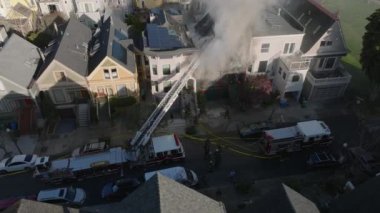 Şehir merkezindeki bir evde profesyonel itfaiyecilerin yangına müdahalesinin hava kaydırak ve pan görüntüsü. San Francisco, California, ABD