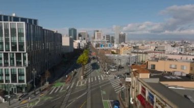 Metropolis 'teki caddenin üzerinde altın saat uçuyor. Geniş bulvarda giden araçlar, arka planda çok katlı binalar. San Francisco, California, ABD