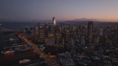 Sahildeki aydınlık gökdelenlerin renkli alacakaranlık gökyüzüne karşı inanılmaz hava görüntüleri. San Francisco, California, ABD