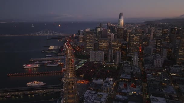 黄昏时分飞越都市上空 沿海公路和河岸码头的空中录像 一群市中心的摩天大楼 窗户明亮 美国加利福尼亚州旧金山 — 图库视频影像