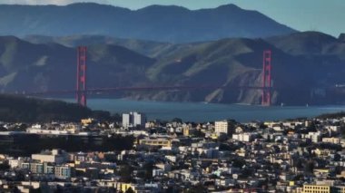 Meşhur Golden Gate Köprüsü 'nün yakınlaştırılmış görüntüsü geniş boğaza yayılıyor. Şehir merkezindeki binalar ön planda. San Francisco, California, ABD