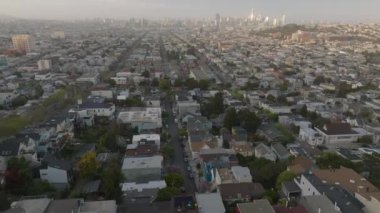 Şehirdeki yerleşim yerlerindeki sıra sıra aile evlerinin hava panoramik görüntüleri. Şehir merkezindeki gökdelenlerin olduğu bir gökyüzü. San Francisco, California, ABD