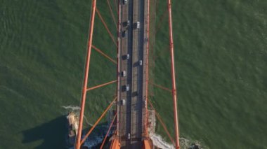 Altın saatinde dalgalı suyun üzerindeki geniş asma köprünün yüksek açılı görüntüsü. Golden Gate Köprüsü 'nde araçlar sürüyor. San Francisco, California, ABD.