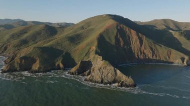 Okyanus kıyısı doğasının hava görüntüleri. Kayalara çarpan ve su sıçratan suya eğil. Altın saatte Diablo Light 'ı göster. San Francisco, California, ABD.