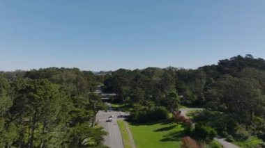 İleriye doğru parktaki yolun üzerinden uçuyor. Şehir merkezindeki gökdelenlerin uzaklığını gösteriyor. San Francisco, California, ABD.