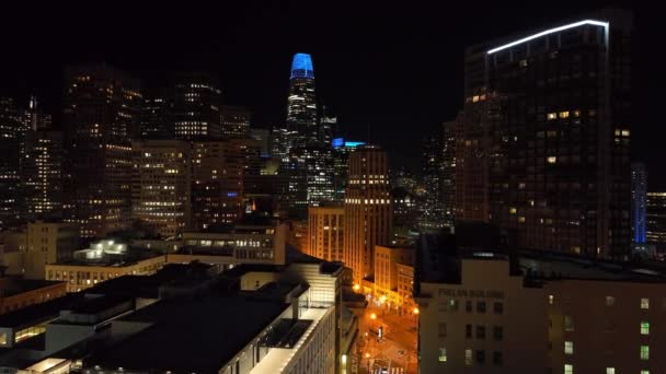 夜は街の上を飛ぶ 高層オフィスや住宅ビルがライトアップされます 米国カリフォルニア州サンフランシスコ — ストック動画