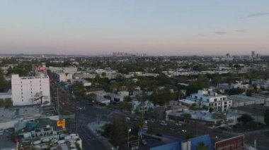 Alacakaranlıktaki şehir manzarası. Şehirdeki binaların ve caddelerin üzerinden uç, şehir merkezindeki gökdelenlerin üzerinden. Los Angeles, Kaliforniya, ABD