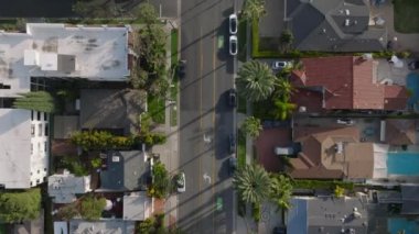 Şehir merkezindeki cadde boyunca uzanan binaların baştan aşağı tarama görüntüleri. Yol tropikal palmiye ağaçlarıyla kaplı. Los Angeles, Kaliforniya, ABD