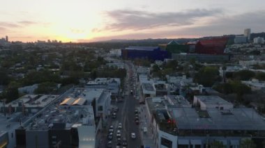 Büyük şehirde, işlek caddenin üzerinde ilerliyorlar. Romantik renkli günbatımı gökyüzü. Los Angeles, Kaliforniya, ABD