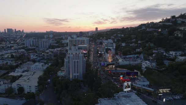 カラフルな夕暮れの空に対する都市の建物や大規模な広告の空中ビュー サンセット ブールバードの交通量が多い 米国カリフォルニア州ロサンゼルス — ストック動画