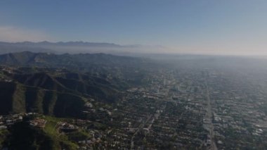 Büyük şehrin ve etrafındaki tepelerin hava panoramik görüntüleri. Sisten yükselen uzak yüksek dağ sırtı. Los Angeles, Kaliforniya, ABD.