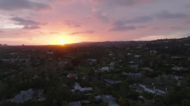 Romantik renkli günbatımına karşı geniş evleri olan lüks yerleşim yerlerinin havadan panoramik manzarası. Los Angeles, Kaliforniya, ABD