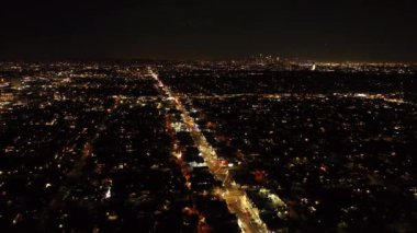 Gece şehrinin üzerinden geriye doğru uçuyor. Şehir merkezinde geniş bir bulvarda aydınlandı. Los Angeles, Kaliforniya, ABD