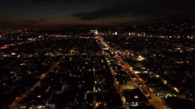 Gece şehrinin hava panoramik görüntüleri. Şehir merkezinin üzerinden uç, ışıklı bulvarda trafik var. Los Angeles, Kaliforniya, ABD