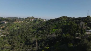 Ormanlık tepenin üzerinden uç. Vadi ve şehir merkezindeki yüksek katlı ofis binalarıyla evleri gözler önüne sermek. Los Angeles, Kaliforniya, ABD.
