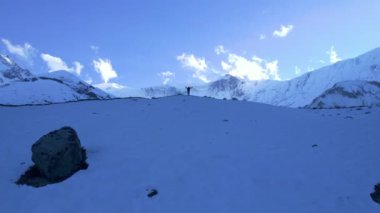 Manzaranın üzerinde uçan erkek yürüyüşçü kollarını kaldırarak yükseliyor. Yürüyüş hedefine ve amacına ulaşmanın keyfini çıkarıyor. Açık hava macerası, Himalaya, Asya, Tilicho 'da yürüyüş..