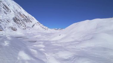 Havadan yükselen görüntüler Himalayalar 'daki dağlarda Tilicho Gölü' nün arka planında karlı yürüyüş yapan yürüyüşçüleri gösteriyor. Annapurna gezisi. Manang. Nepal 'de. Asya.