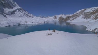 Havadan kuşların bakış açısı, kollarını kaldırmış, ilham verici yalnız erkek yürüyüşçünün üzerinde uçar. Nepal 'deki Tilicho Gölü' ne ulaşmanın tadını çıkar. Yolculuk macera yaşam tarzı, Tilicho, Himalayalar 'a kadar..