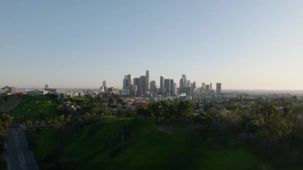 空中全景的绿色植被在城市和天际与著名的市中心摩天大楼与晴朗的天空 美国加利福尼亚州洛杉矶 — 图库视频影像