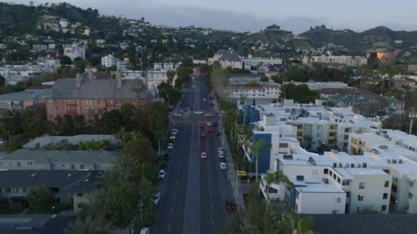前方住宅街の広いマルチレーン通りの上を飛ぶ 夕暮れ時の都市の交通の空中ビュー 米国カリフォルニア州ロサンゼルス — ストック動画