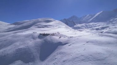 Güneşli bir günde, yüksek irtifada Himalaya dağlarında yürüyüş yapan turist gruplarının üzerinden uçan hava aracı. Tilicho Gölü yürüyüş rotası, Manang, Nepal.