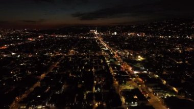 Gece şehrinin hava panoramik görüntüleri. Şehir merkezinin üzerinden uç, ışıklı bulvarda trafik var. Los Angeles, Kaliforniya, ABD